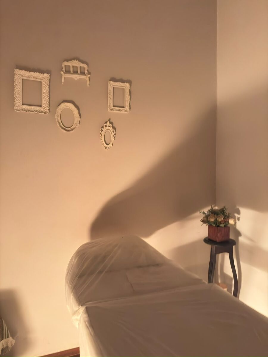 Parede com molduras decorativas e arranjo de flores ao lado da maca