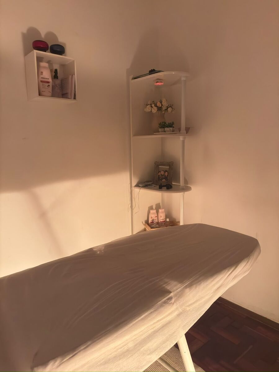 Prateleira com flores, óleos e equipamentos ao lado da maca